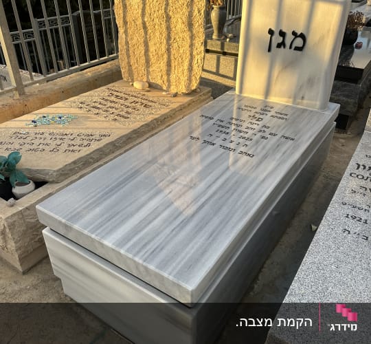 מצבה מאבן שיש עם כיתוב בעברית בבית קברות